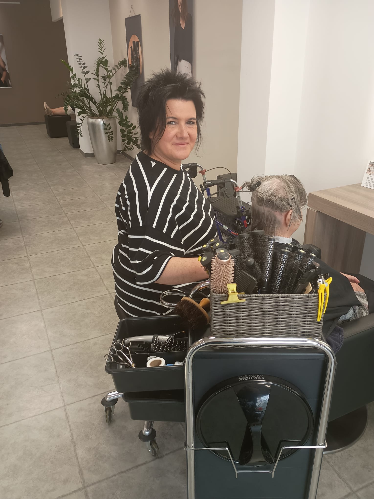 Eine Frau sitzt in einem Friseursalon, während ihr die Haare frisiert werden.