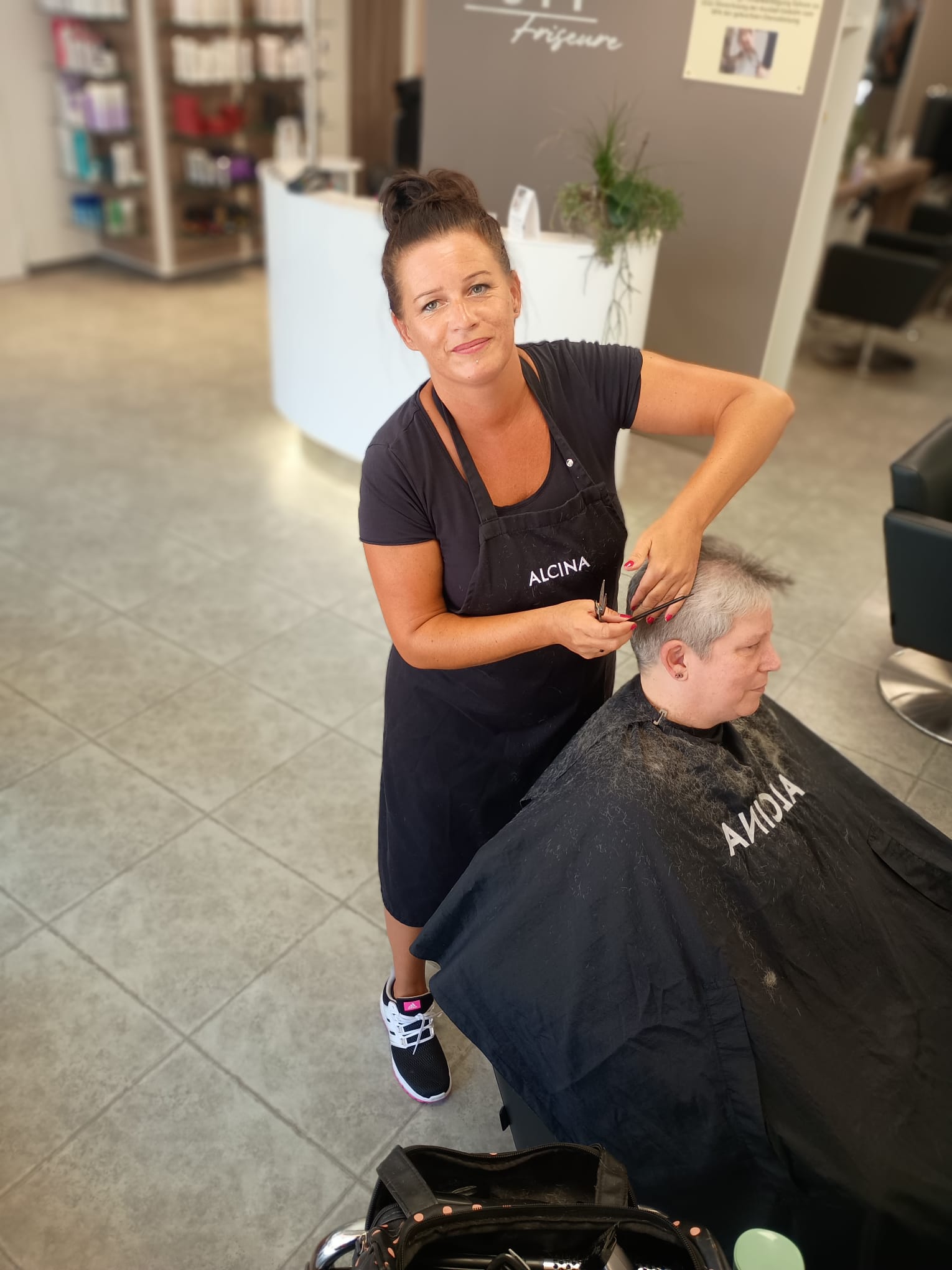 Eine Frau erhält einen Haarschnitt von einer Friseurin in einem stilvollen Salon.
