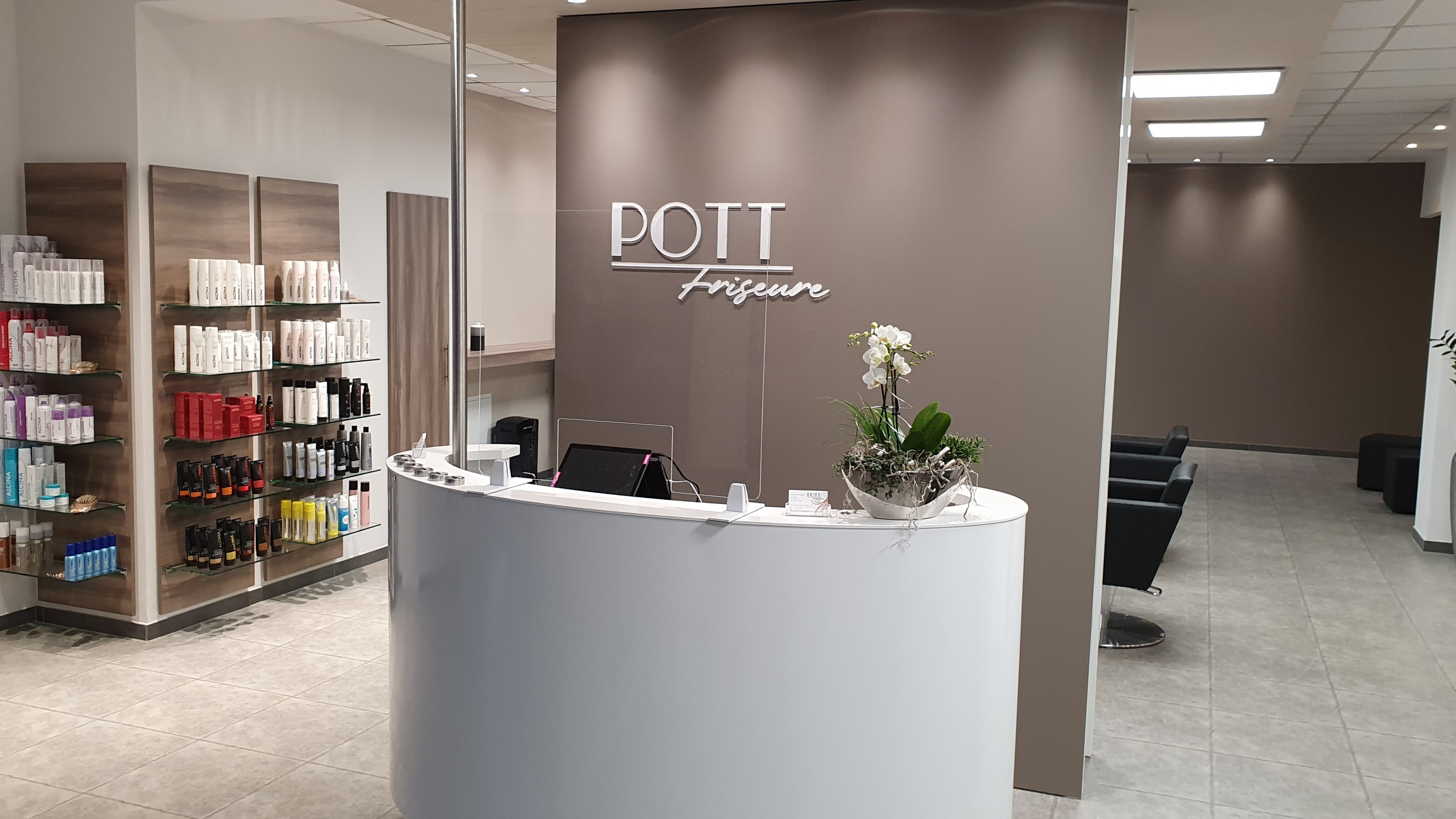 Heller Salon mit weißem Empfangstresen und einem Schild "Salon Pott"